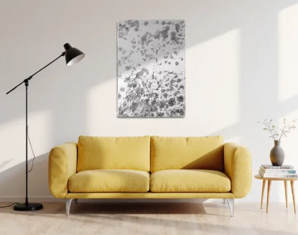 Abstraktes Bild aus weißer und schwarzer Acrylfarbe mit einer Kunststofffolie überzogen. Das Bild, das den Eindruck einer Weltraumaufnahme erweckt, hängt in einem Raum über einem Curry farbigem Sofa. | mixed-art - wolfram schäfers