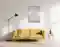 Das Bild zeigt ein Wohnzimmer mit einem gelben Sofa, einer Stehlampe und einem abstrakten Wandbild mit durchsichtiger Folie. Auf einem Beistelltisch stehen eine Vase mit Pflanzen und Bücher. Das Bild zeigt ein Wohnzimmer mit einem gelben Sofa, einer Stehlampe und einem abstrakten Wandbild mit durchsichtiger Folie. Auf einem Beistelltisch stehen eine Vase mit Pflanzen und Bücher.